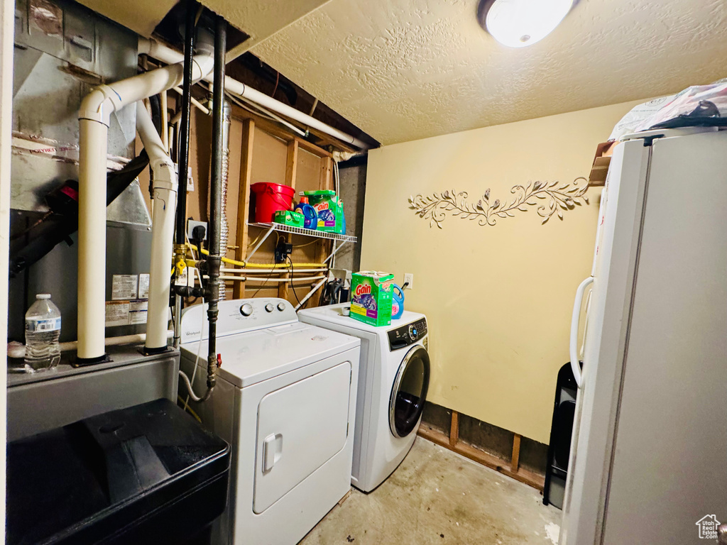 Washroom featuring independent washer and dryer and a textured ceiling