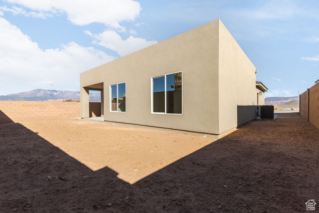 Back of property with a fenced backyard, central AC unit, and stucco siding