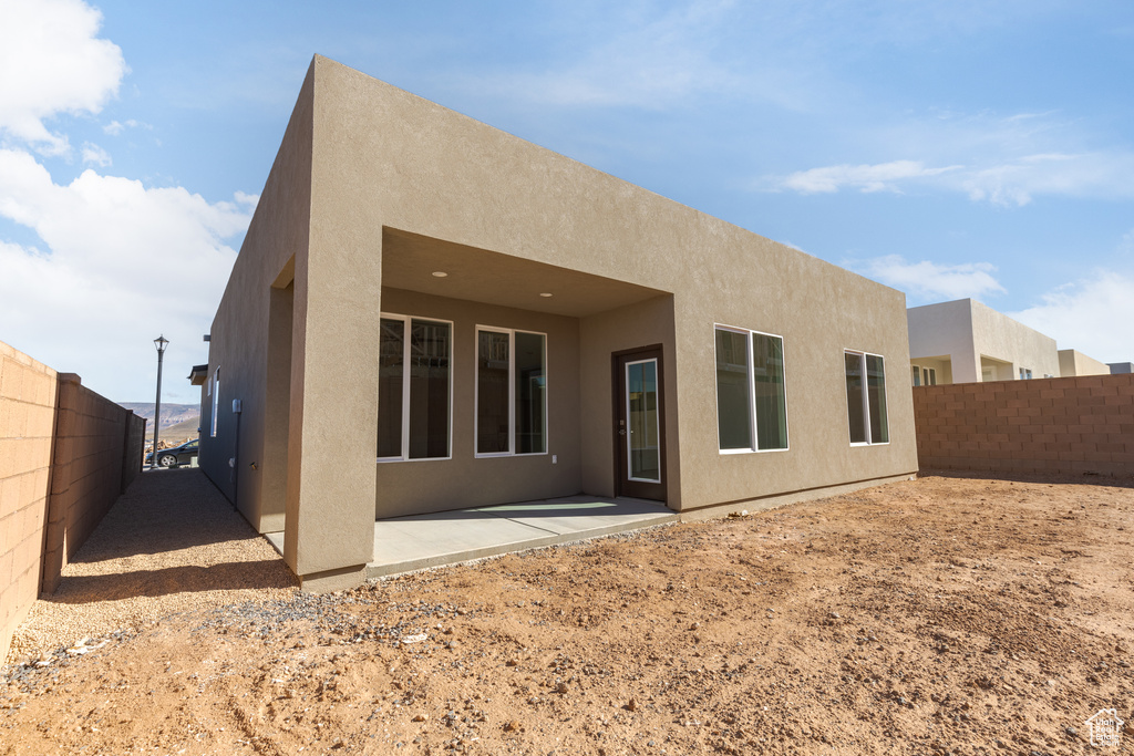 Back of house with stucco siding and a patio