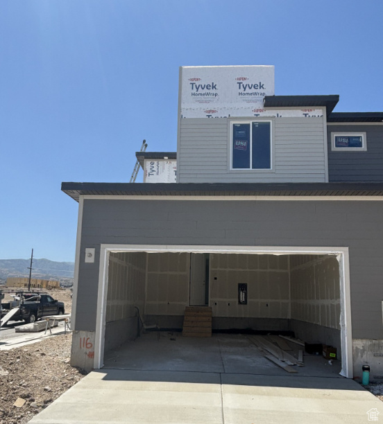 Back of house featuring a mountain view and concrete driveway