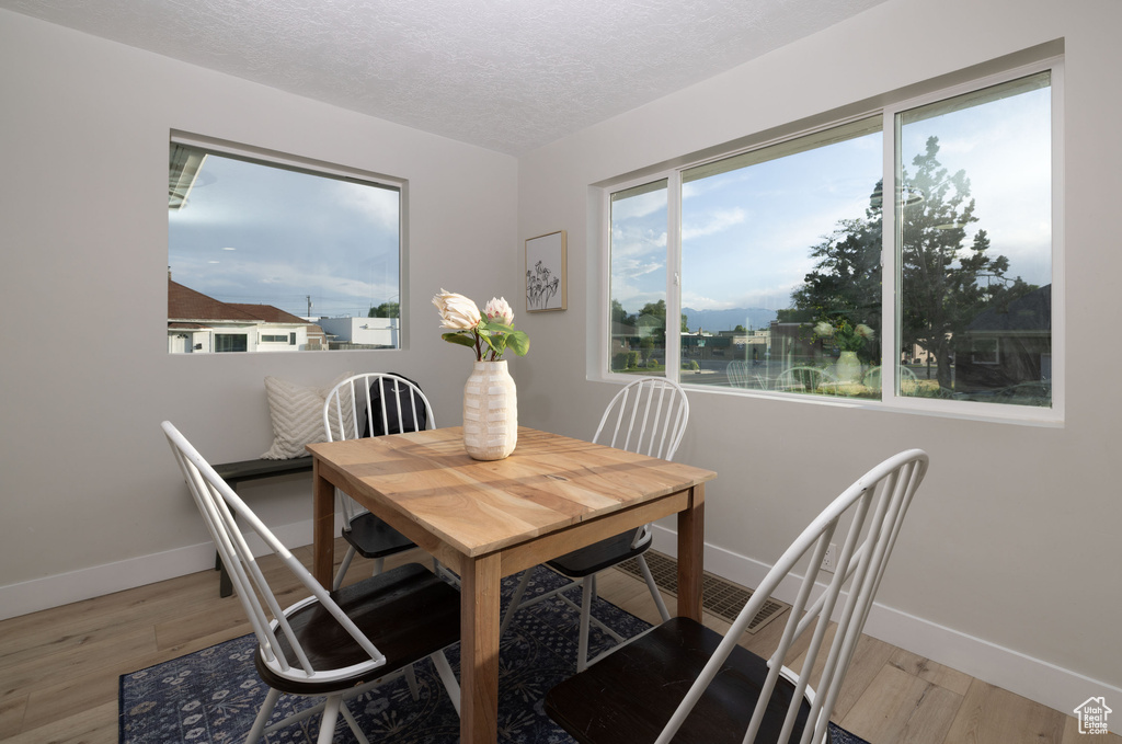 Dining area featuring baseboards, light wood finished floors, and a textured ceiling