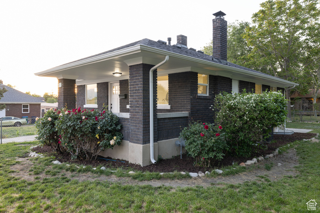 View of property exterior featuring brick siding and a chimney
