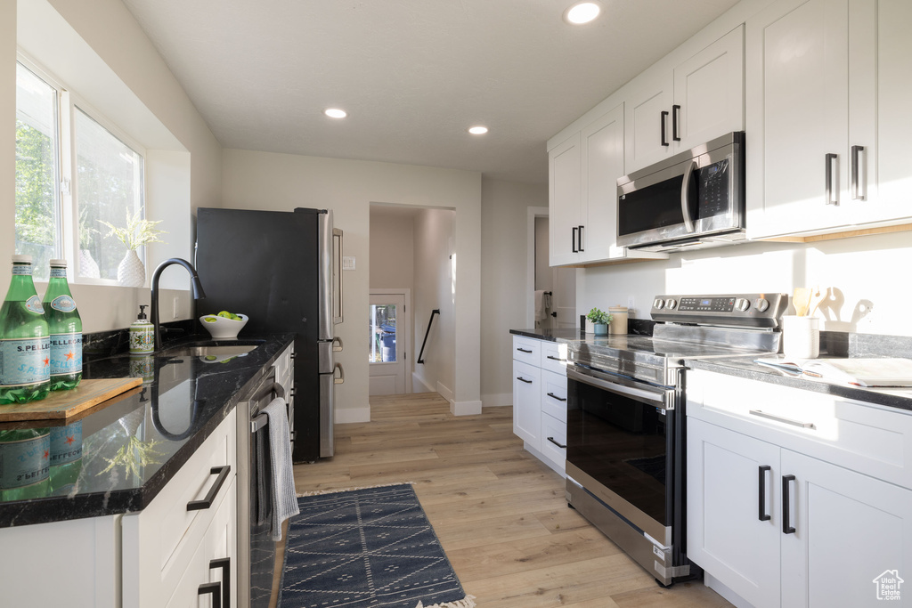Kitchen with stainless steel appliances, a sink, light wood-type flooring, recessed lighting, and white cabinets