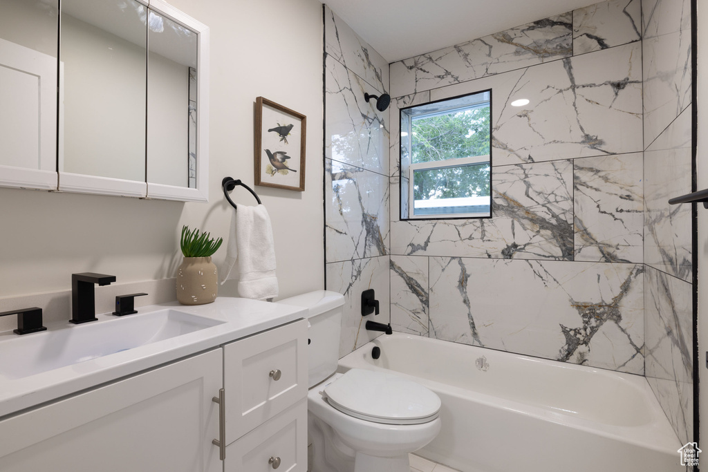 Bathroom featuring toilet, vanity, and shower / tub combination