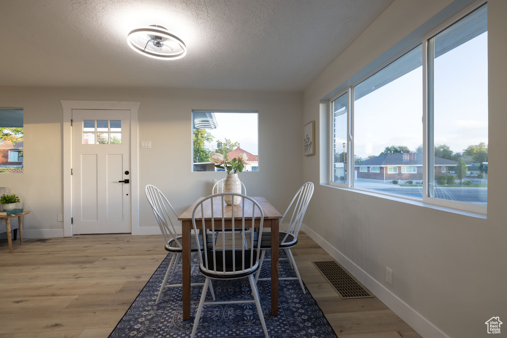Dining area featuring light wood-style flooring, baseboards, and a textured ceiling