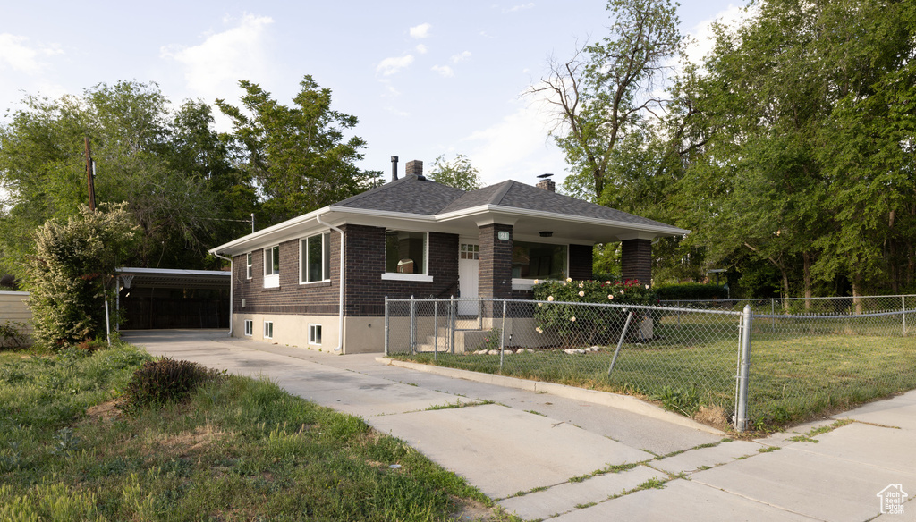 Bungalow with brick siding, a carport, a chimney, driveway, and covered porch
