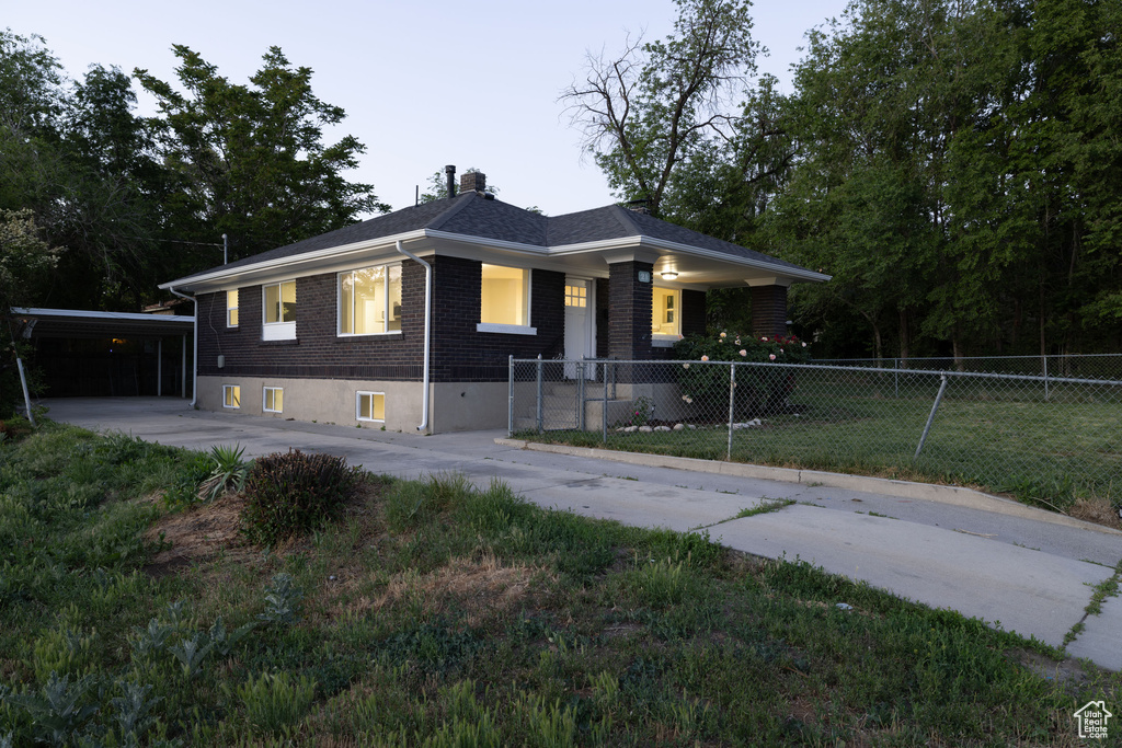 View of front facade with brick siding, a chimney, concrete driveway, and a carport