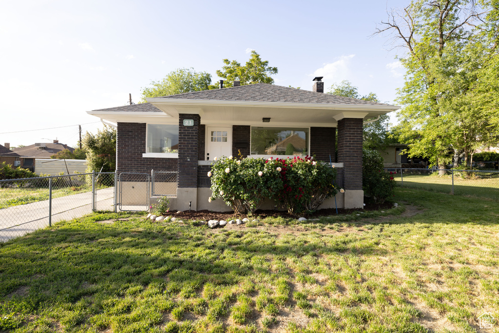 Bungalow-style house with brick siding, a chimney, and a gate