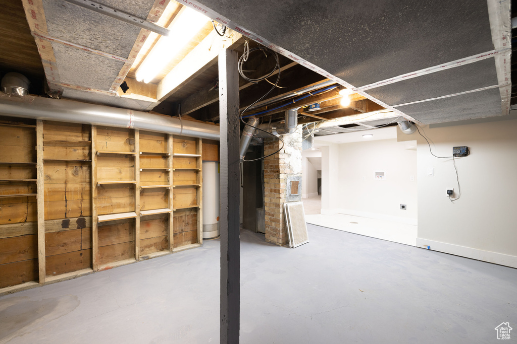 Unfinished below grade area featuring gas water heater and baseboards