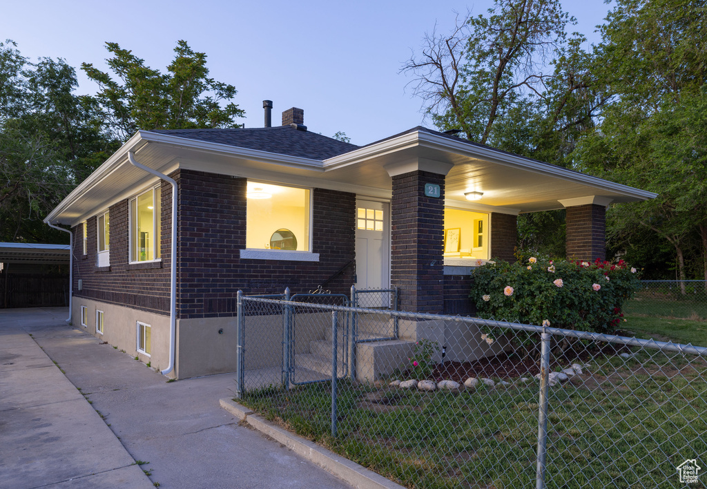 Single story home featuring brick siding, a chimney, driveway, and a porch