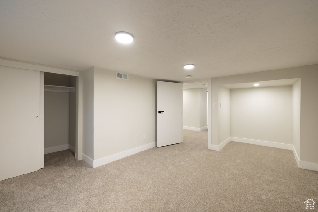 Finished below grade area featuring light carpet and baseboards