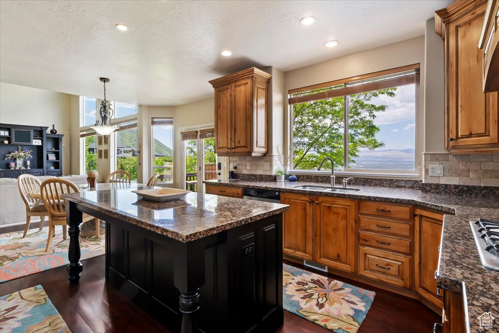 Kitchen with a sink, dark wood-style flooring, brown cabinets, and recessed lighting