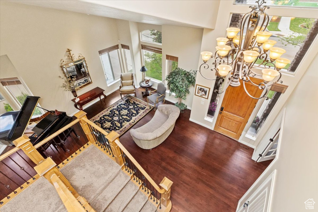 Foyer featuring a towering ceiling, wood finished floors, a chandelier, and baseboards