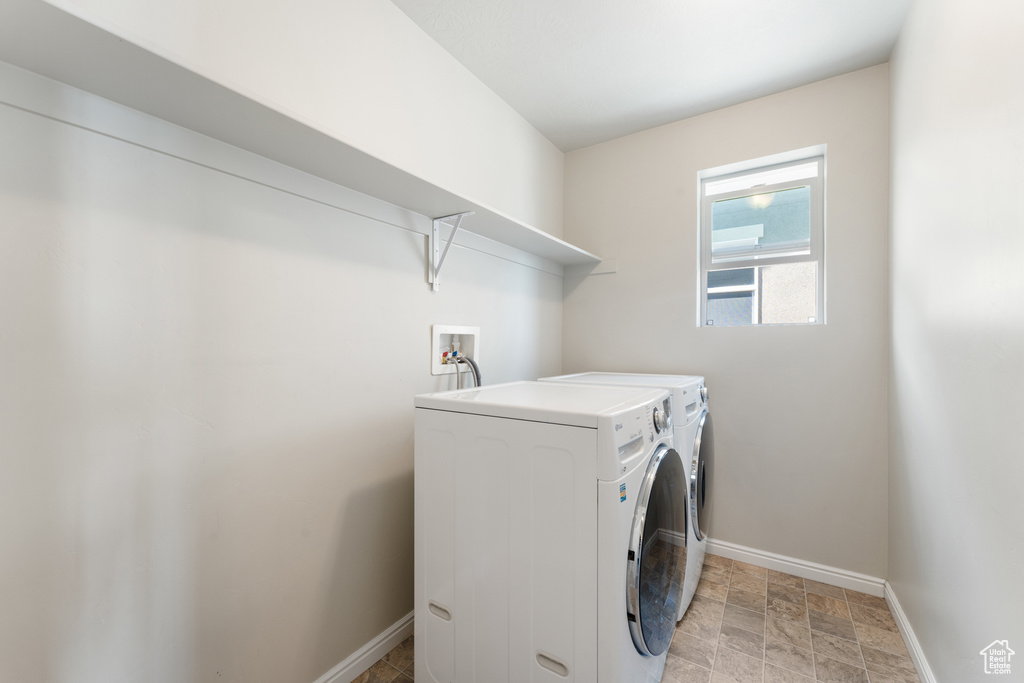 Laundry area with washer and dryer, baseboards, and stone finish floors