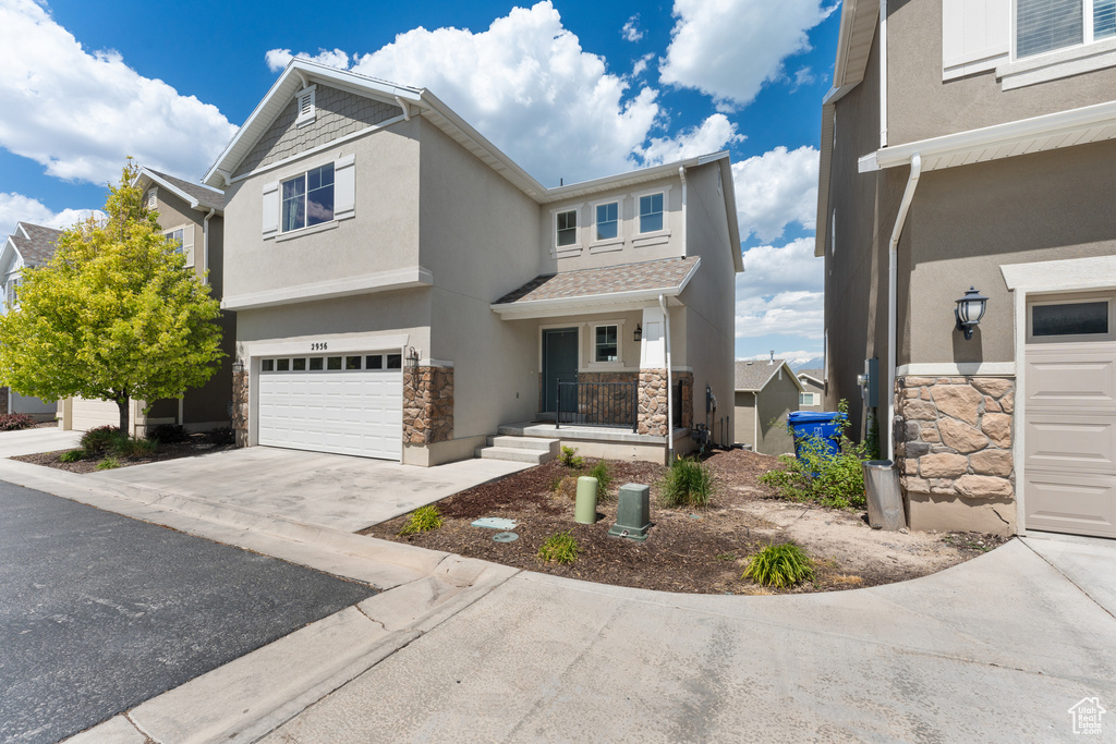 View of front of home with stone siding, stucco siding, a garage, and concrete driveway