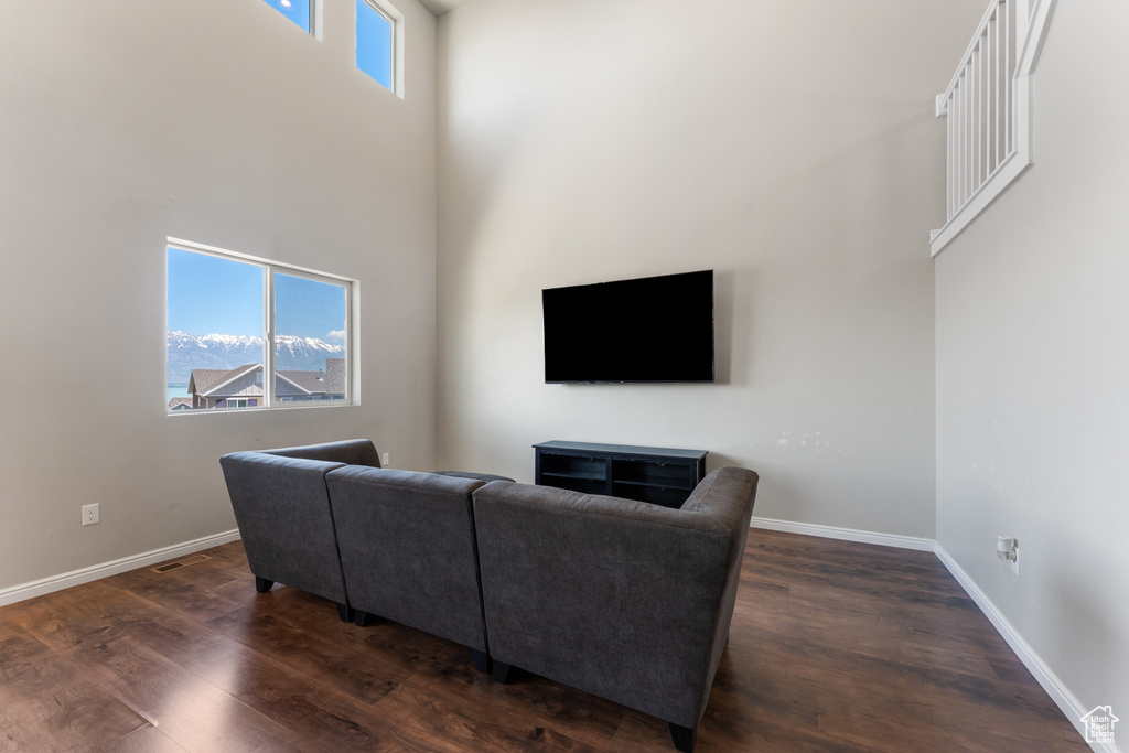 Living room featuring baseboards, dark wood-style floors, and a towering ceiling