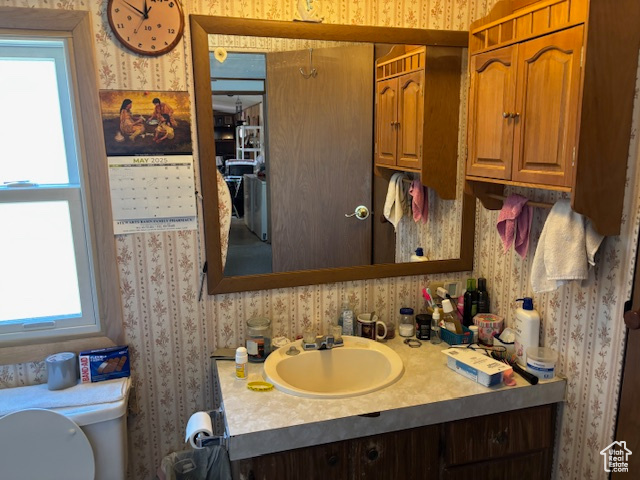 Bathroom featuring wallpapered walls, vanity, plenty of natural light, and toilet