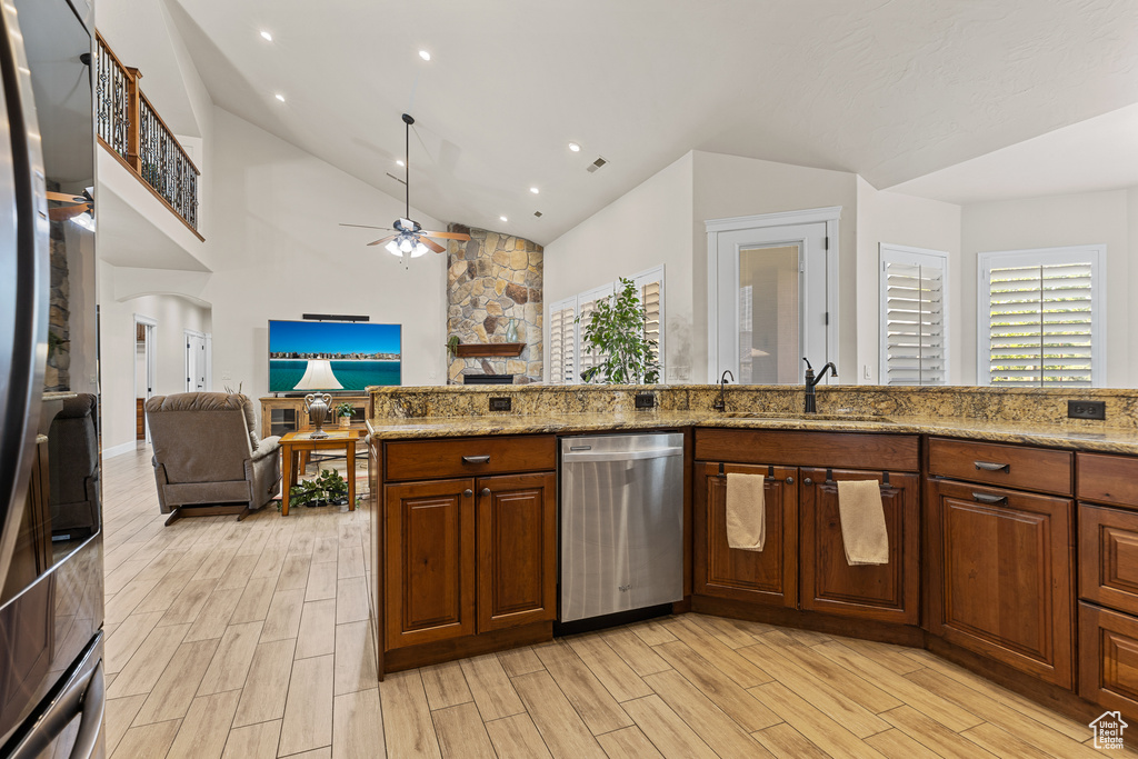 Kitchen with dishwasher, a sink, a ceiling fan, light wood-style flooring, and high vaulted ceiling