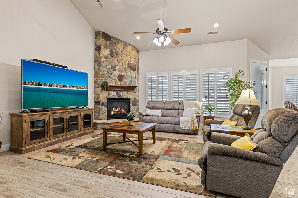 Living room with ceiling fan, wood finished floors, a fireplace, and vaulted ceiling