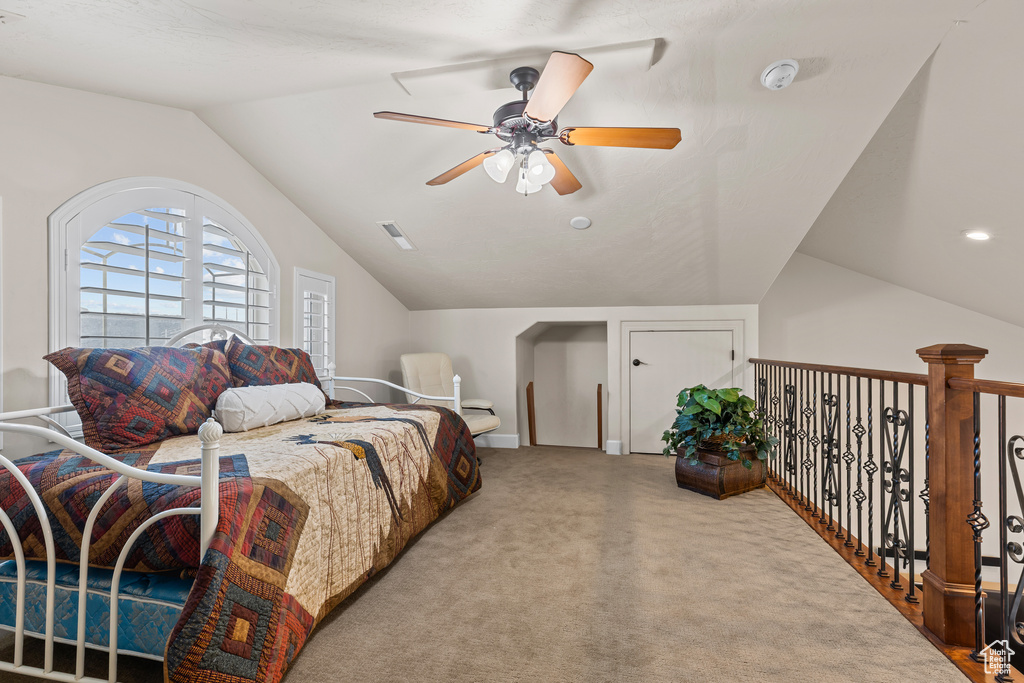 Carpeted bedroom featuring lofted ceiling and a ceiling fan