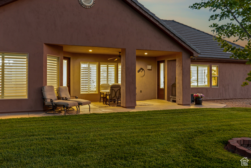 Rear view of property with a patio area, ceiling fan, a yard, and stucco siding