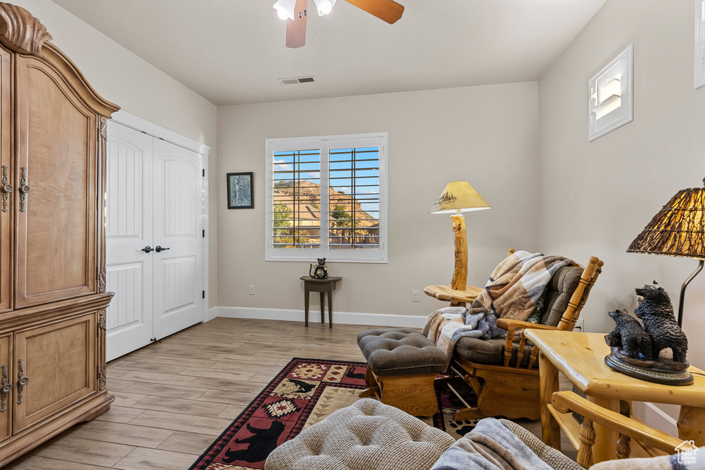 Sitting room with light wood finished floors, a ceiling fan, and baseboards