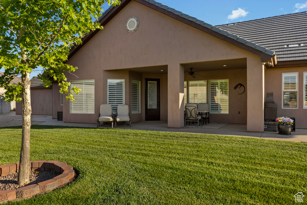 Back of property featuring ceiling fan, a patio, stucco siding, a yard, and a tile roof