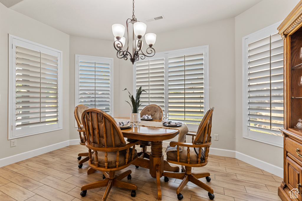 Dining space featuring a chandelier, light wood-style floors, baseboards, and a desk