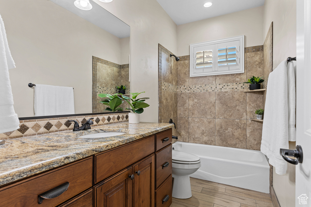 Bathroom featuring vanity, toilet, bathing tub / shower combination, and wood finished floors