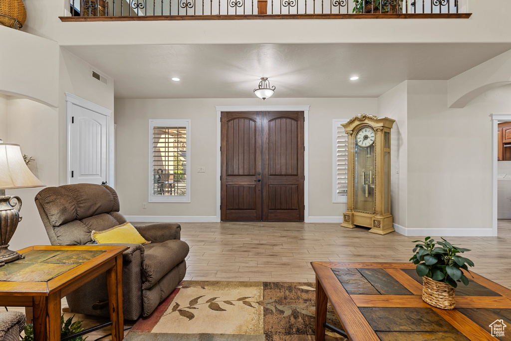 Living area featuring arched walkways, light wood finished floors, baseboards, and recessed lighting