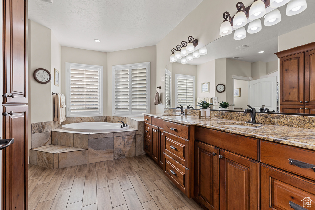 Bathroom with a garden tub, double vanity, and wood finished floors