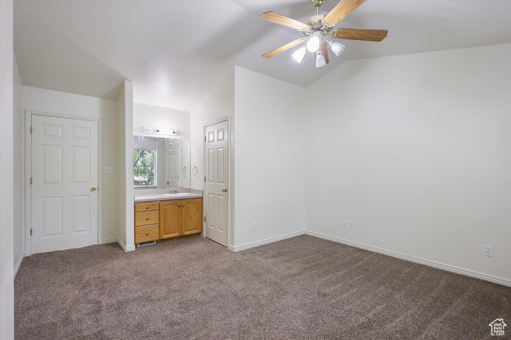 Unfurnished bedroom featuring vaulted ceiling, carpet floors, a sink, baseboards, and ensuite bathroom