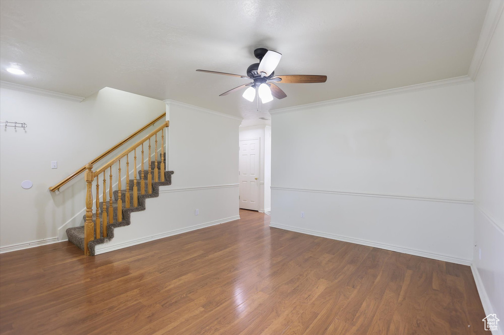 Unfurnished room featuring stairs, ceiling fan, ornamental molding, wood finished floors, and baseboards