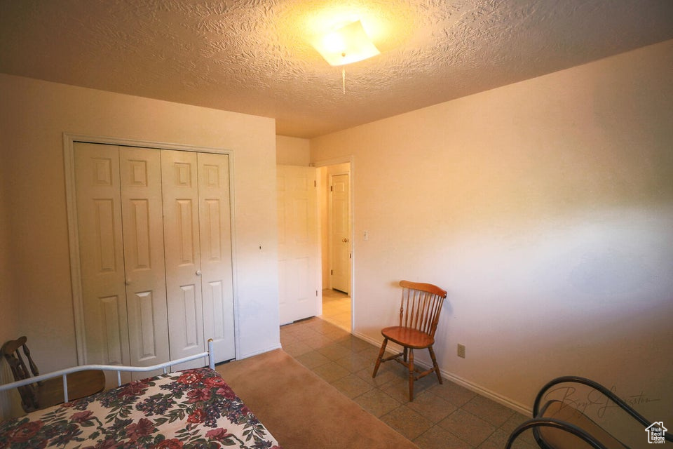 Bedroom featuring a textured ceiling, a closet, and baseboards