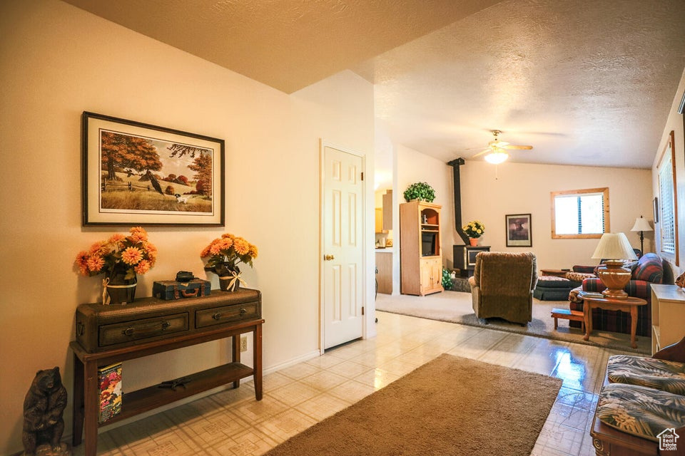 Living area with a textured ceiling, lofted ceiling, ceiling fan, light tile patterned floors, and baseboards