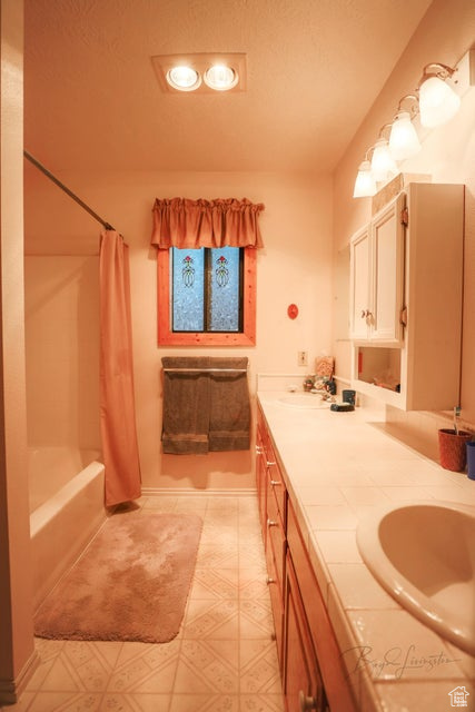 Bathroom featuring double vanity and shower / bath combo