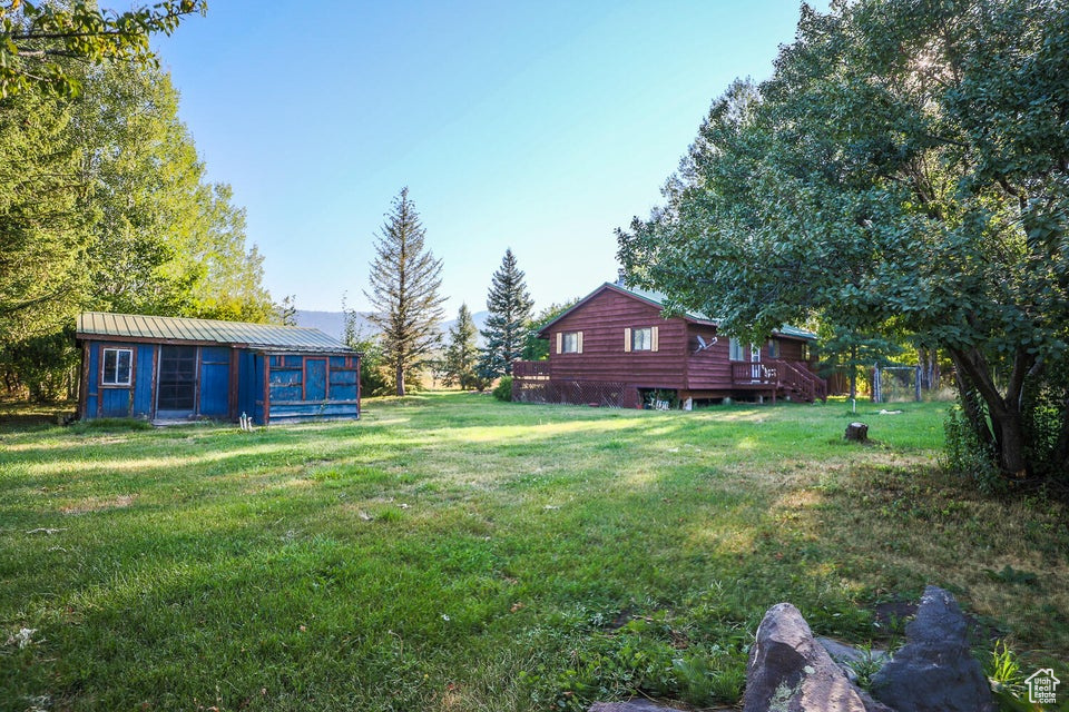 View of grassy yard featuring an outbuilding and a deck