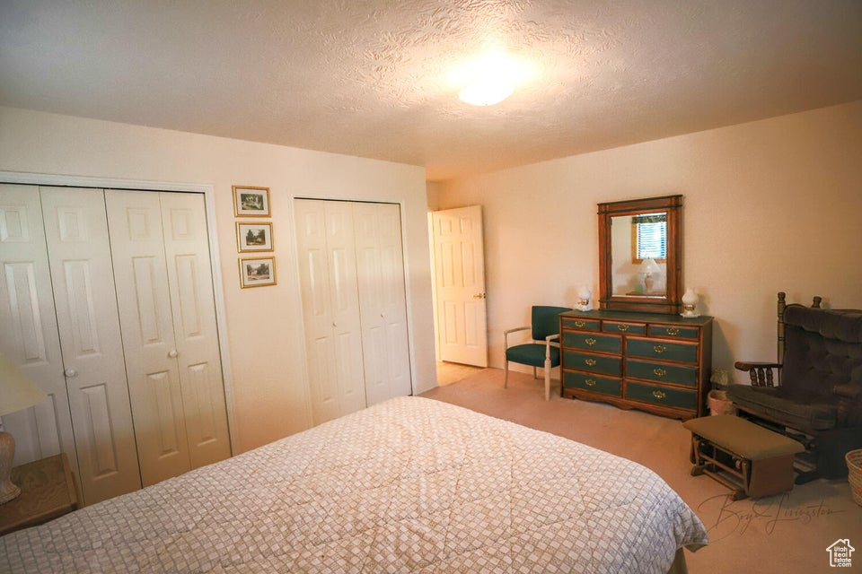 Bedroom featuring two closets, carpet floors, and a textured ceiling