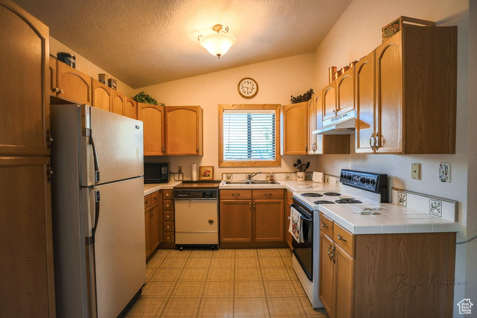 Kitchen with freestanding refrigerator, electric stove, dishwasher, black microwave, and light flooring