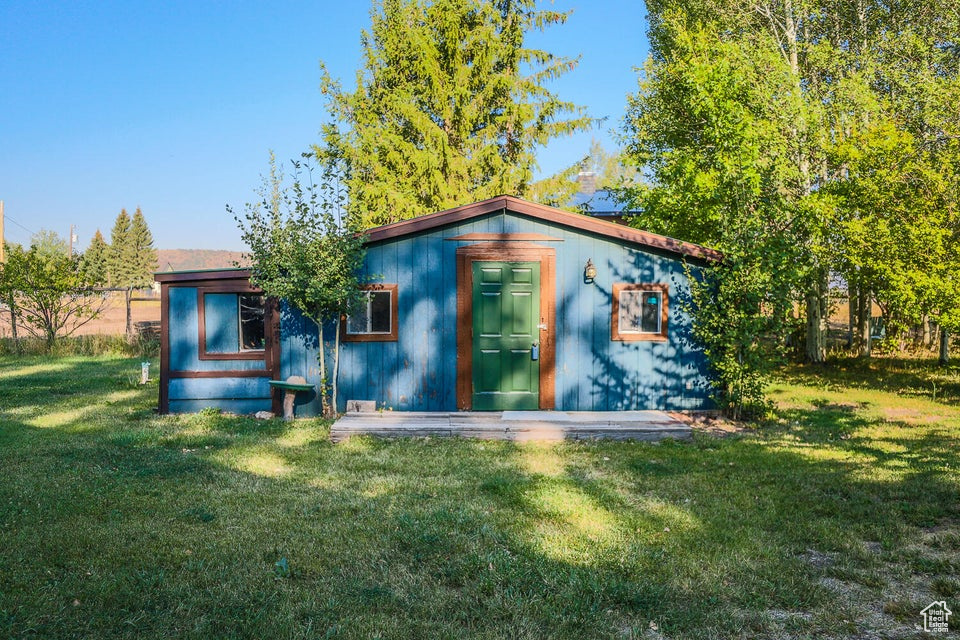 Rear view of property featuring a yard and an outdoor structure