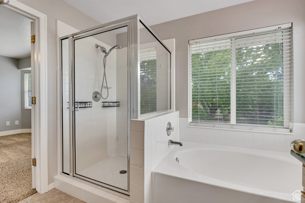 Full bath with a bath, a stall shower, and baseboards
