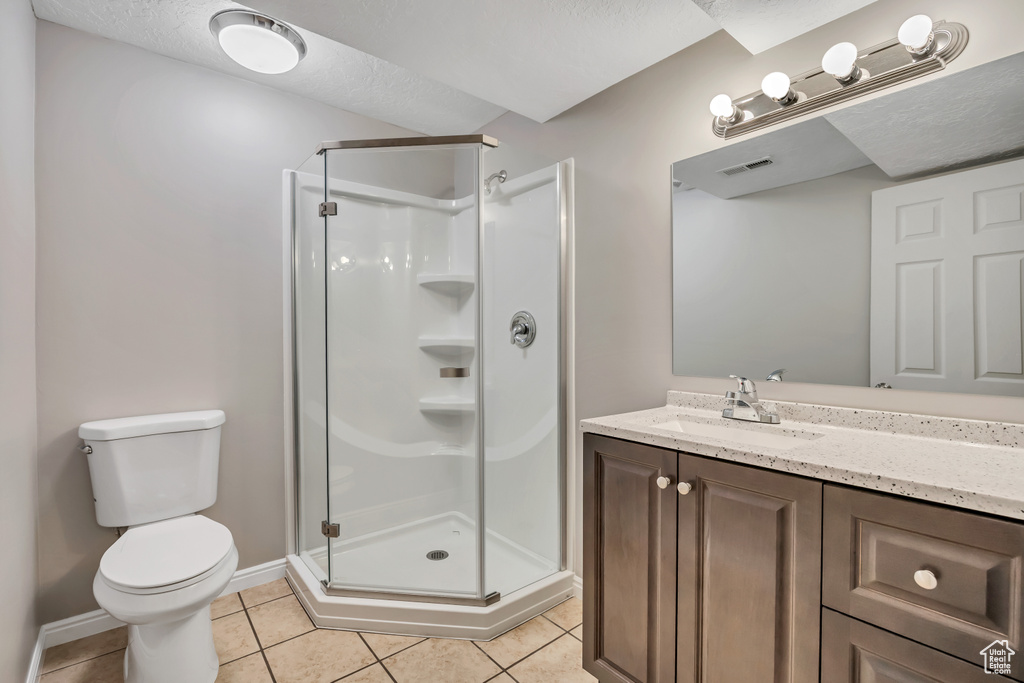 Full bath featuring a stall shower, toilet, and tile patterned flooring