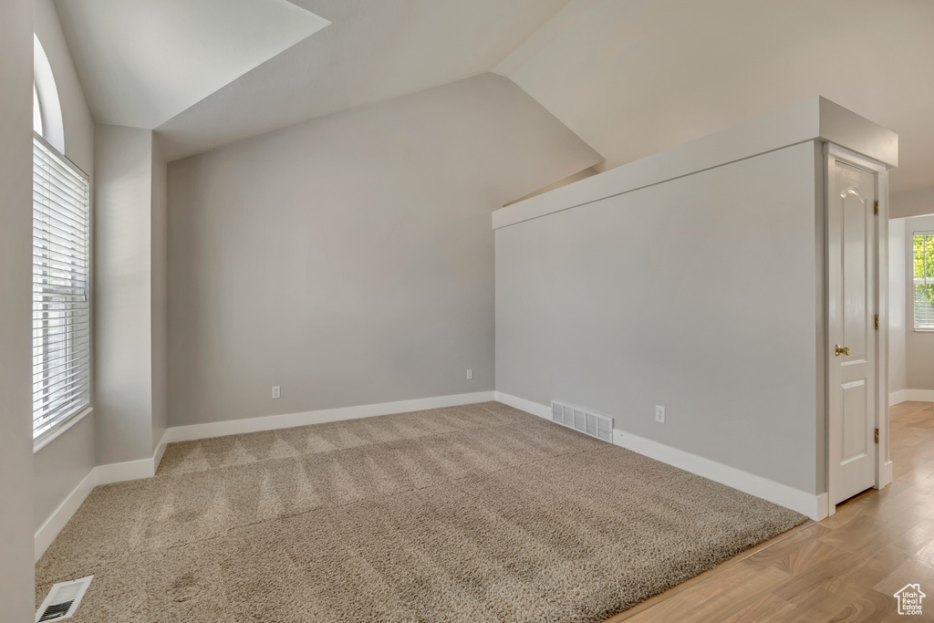 Bonus room with lofted ceiling, baseboards, and light wood-type flooring