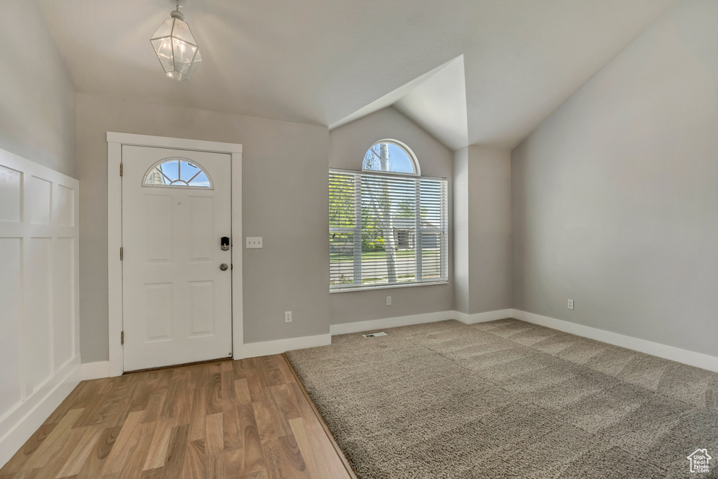 Entrance foyer featuring lofted ceiling, healthy amount of natural light, wood finished floors, and baseboards