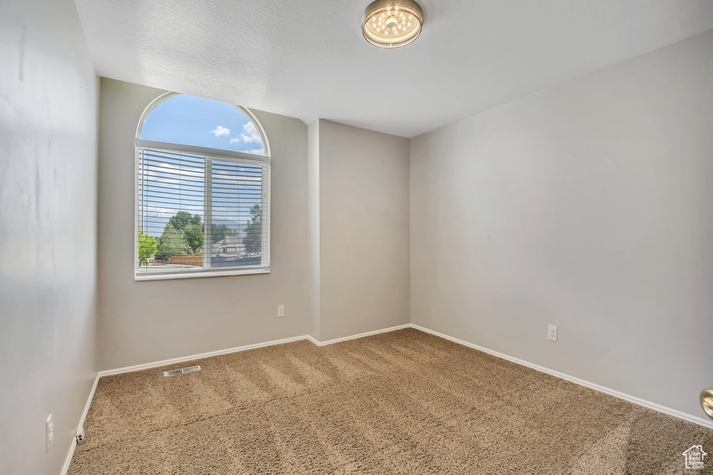 Carpeted spare room featuring baseboards