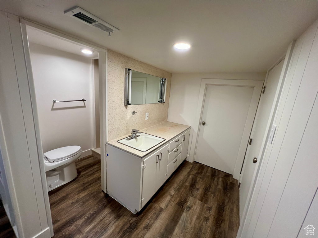Bathroom with vanity, toilet, wood finished floors, and recessed lighting