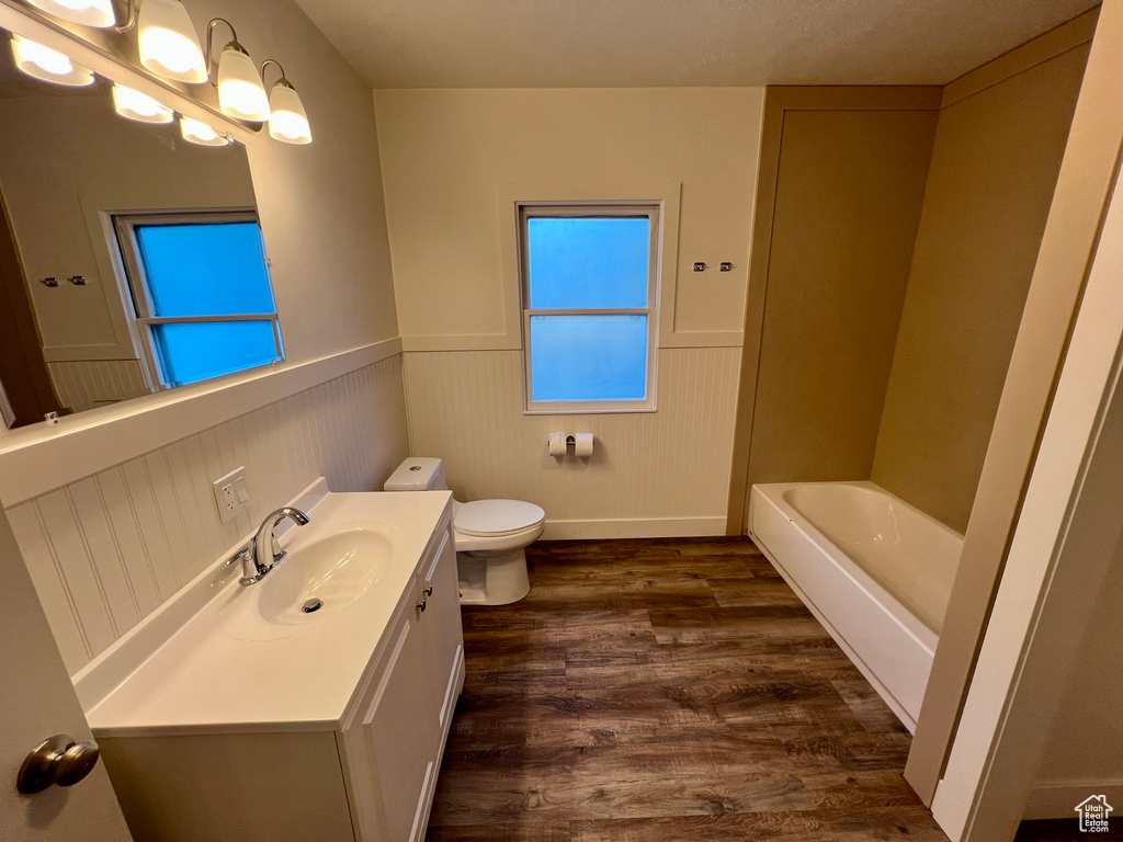 Full bathroom featuring wainscoting, vanity, toilet, wood finished floors, and a bathtub