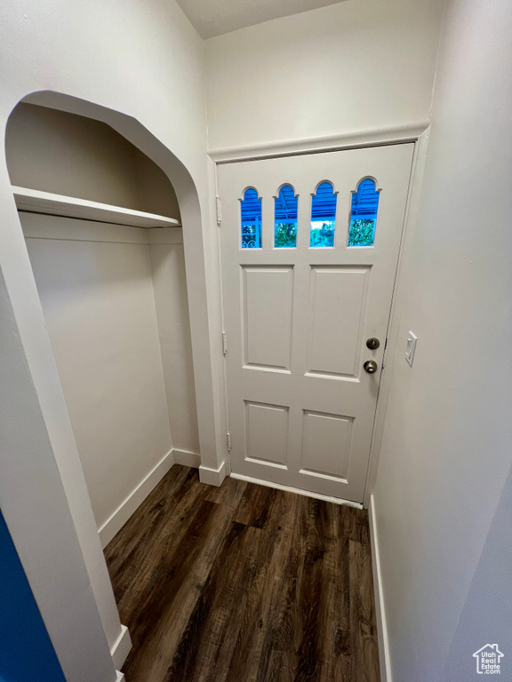 Entrance foyer featuring dark wood-style flooring, baseboards, and arched walkways