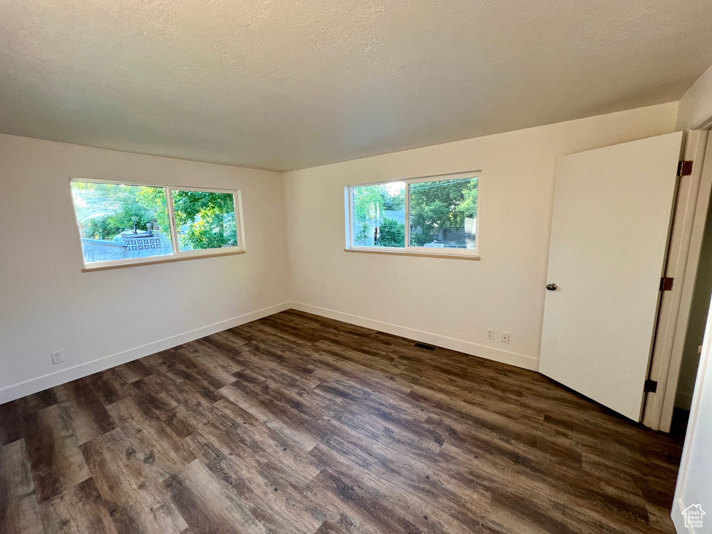Unfurnished room with dark wood-type flooring and baseboards