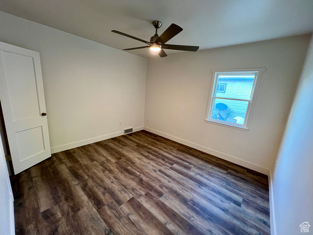 Unfurnished room featuring a ceiling fan, dark wood-style flooring, and baseboards